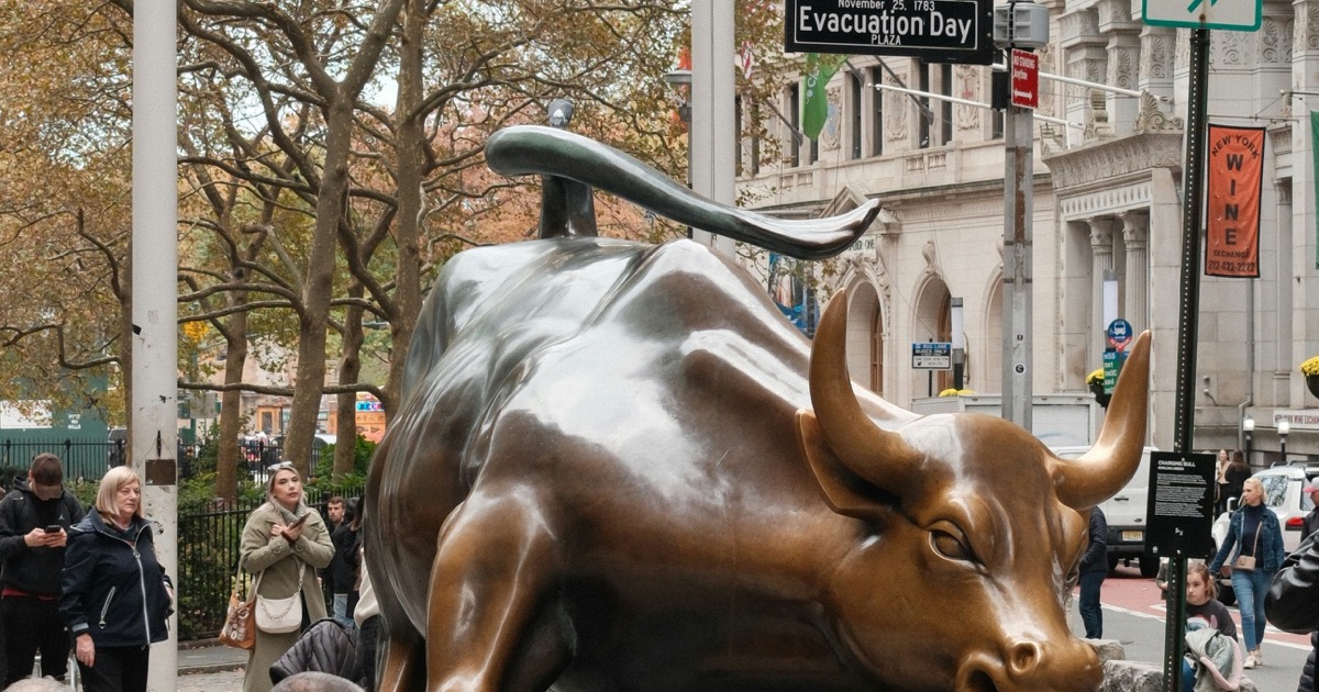 Charging Bull statue on cobblestone street in New York City Financial District symbolizing the historic bull market rally