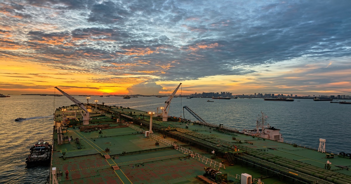 Large tanker ship sailing into harbor at sunset, reflecting oil market surge and end-of-day trading themes