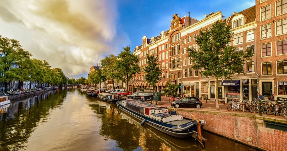 A storm front rolling in over an Amsterdam canal, half the sky clear and half dark — a visible regime change in the weather