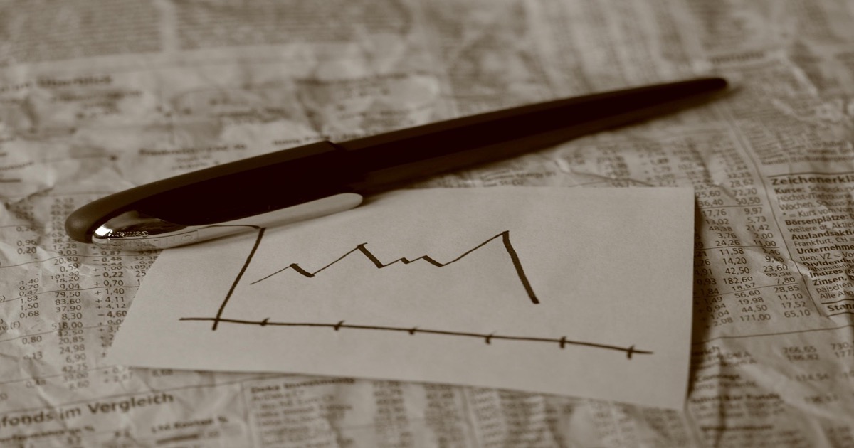 Pen resting on financial chart with newspaper representing morning market analysis and stock market data
