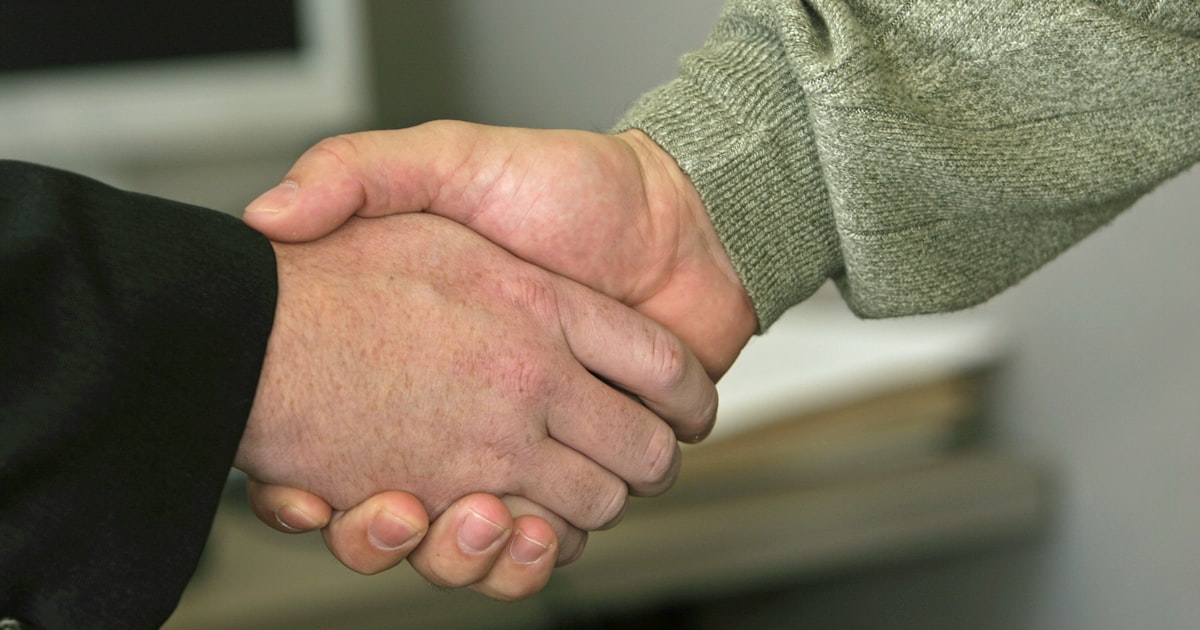 Two people shaking hands representing the ceasefire agreement between the US and Iran