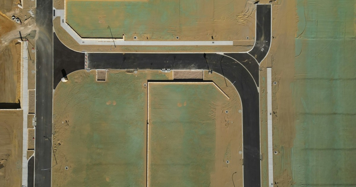 Aerial view of roads and prepared home sites in a new housing development before the August 25, 2026 housing data.