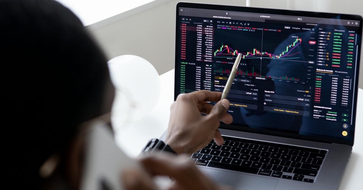 A person reviewing trading charts on a laptop, symbolizing the June 8, 2026 morning market update as futures split, oil jumps and Apple WWDC approaches.