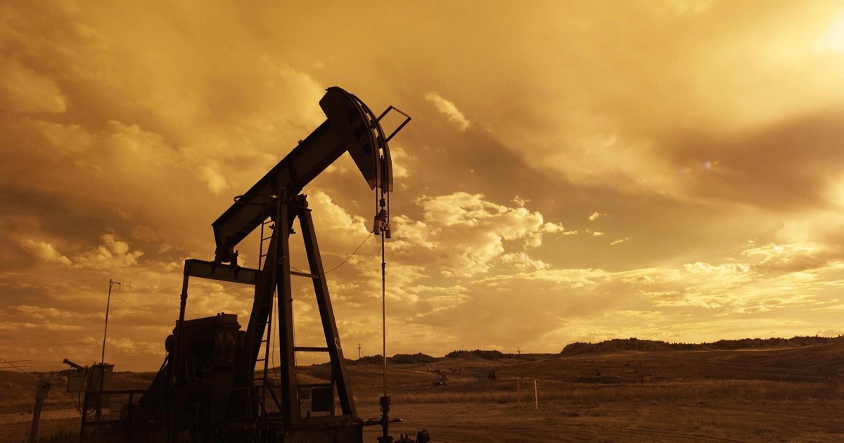 Oil pump jack silhouetted against an orange sunset sky, symbolizing crude prices above $110 amid Middle East tensions.