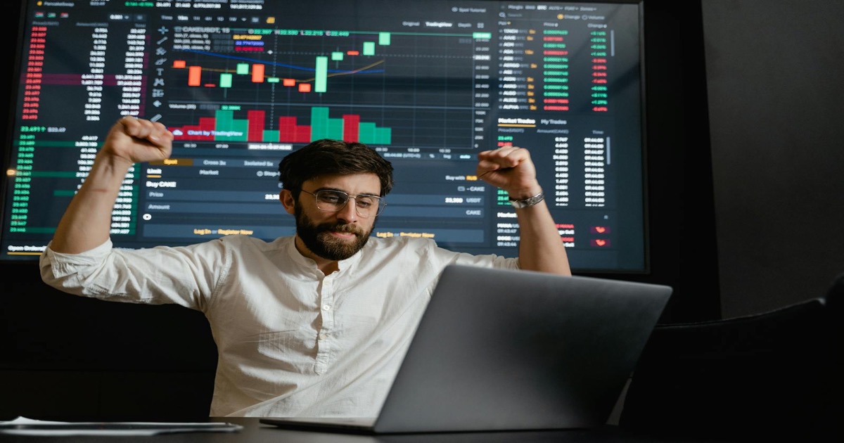A trader studies market charts on a laptop in front of a stock-market display before the May 22 session.