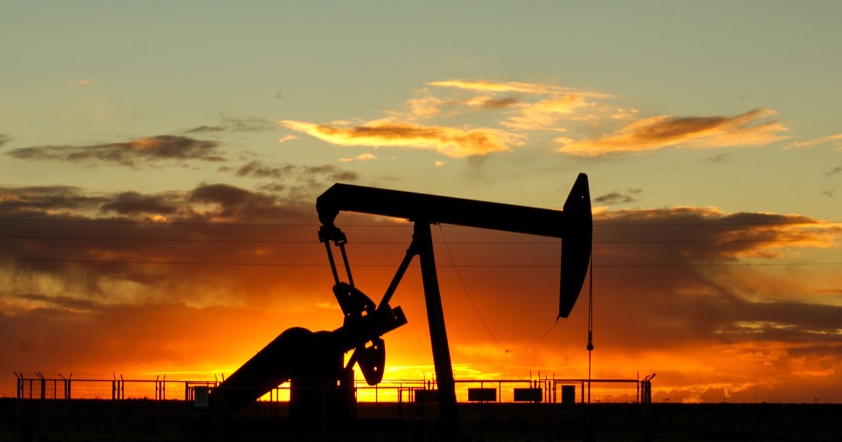 An oil pump jack stands against an orange sunrise as markets weigh high crude prices and inflation data.