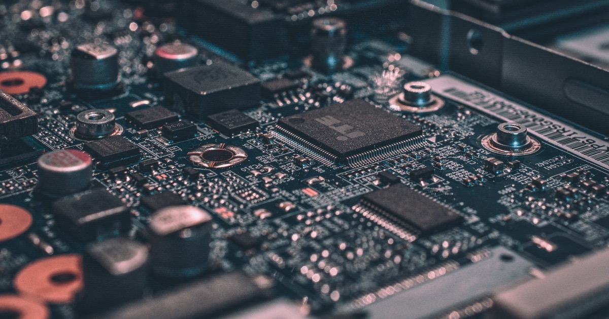 A close view of processors and components on a dark circuit board represents pressure on AI semiconductor shares.