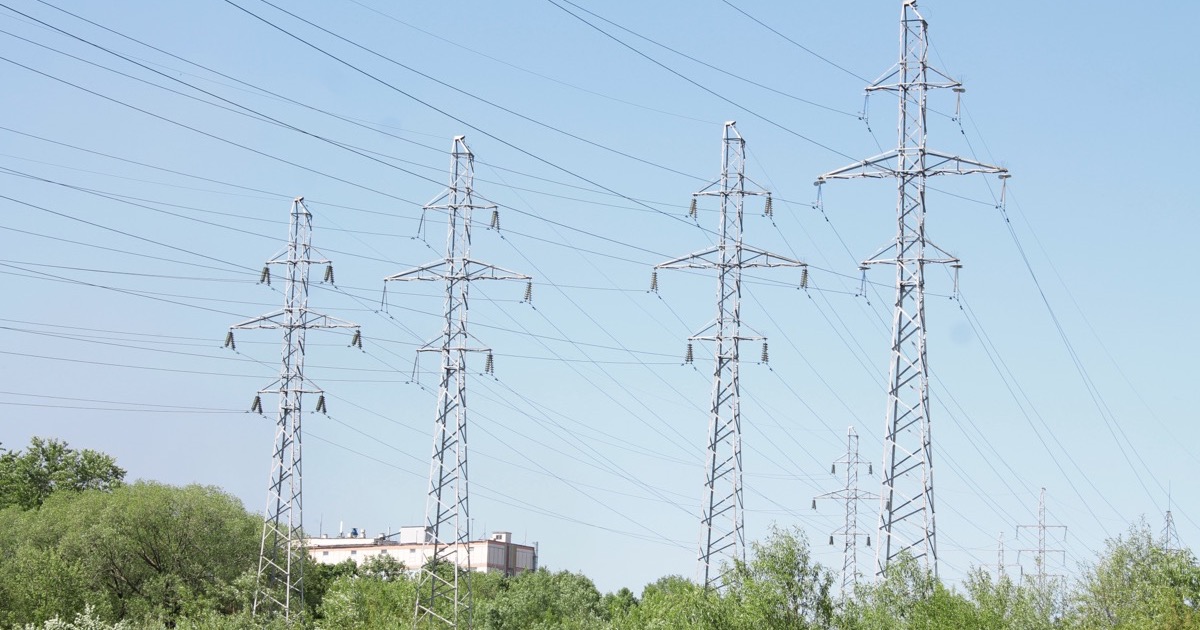 A high-voltage electricity transmission tower against the sky, illustrating the grid-infrastructure bottleneck behind the AI data center boom