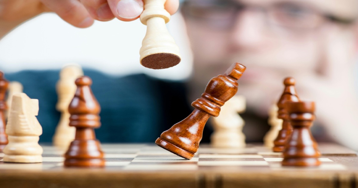 Chess player holding a piece, symbolizing strategic positioning for the week ahead in financial markets