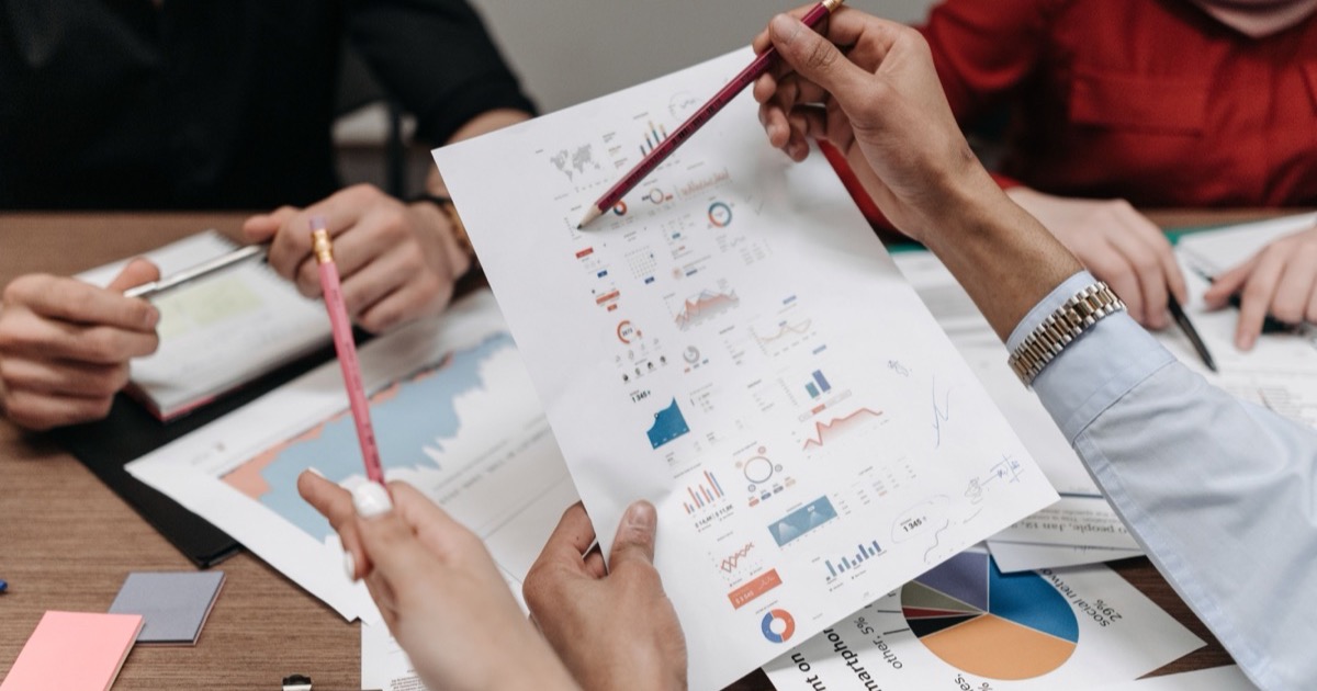 Analysts review printed charts and market reports around a desk, symbolizing the June 15-19, 2026 AlphaEdge Week Ahead Outlook and the portfolio decisions facing investors.