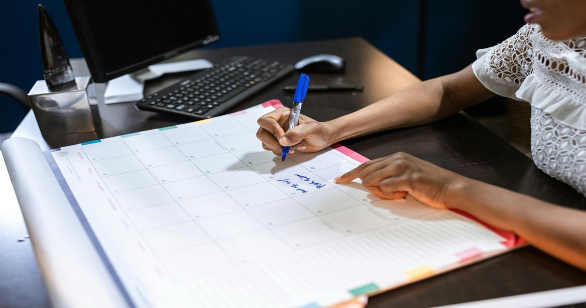 A professional marks a desk calendar beside a keyboard, symbolizing the June 1-5 market calendar for the AlphaEdge Week Ahead Outlook.