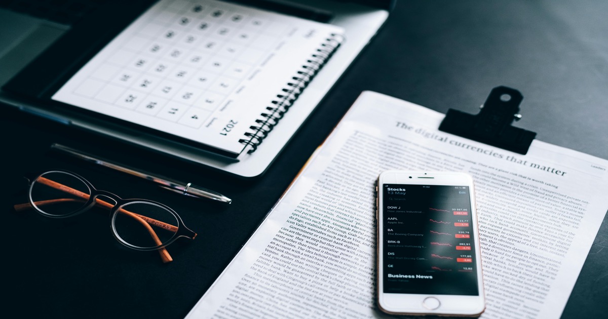 A smartphone with market analytics rests on a clipboard beside financial printouts for the May 18-22 weekly market review.